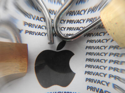 Apple logo hooked by fishing hook over privacy policy text representing targeted exploitation of mobile devices and smartphone surveillance risk